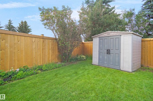 Manicured lawn with mature perimeter trees, wood privacy fencing, and a dedicated storage shed - 907 Jordan Crescent Nw, Edmonton, AB - Outdoor