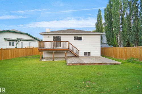 Expansive green lawn, elevated wooden deck, ground-level wooden patio, and full perimeter wood fencing - 907 Jordan Crescent Nw, Edmonton, AB - Outdoor With Deck Patio Veranda