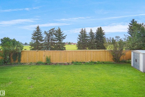 Expansive backyard with a manicured lawn, full wooden privacy fence, mature trees, and a storage shed - 907 Jordan Crescent Nw, Edmonton, AB - Outdoor With Backyard