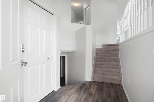 Entryway featuring wood-finish flooring, white paneled doors, a carpeted staircase, and white banisters - 907 Jordan Crescent Nw, Edmonton, AB - Indoor Photo Showing Other Room