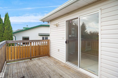 Exterior deck featuring wood flooring and railing, white vinyl siding, and a sliding glass door - 907 Jordan Crescent Nw, Edmonton, AB - Outdoor With Deck Patio Veranda With Exterior