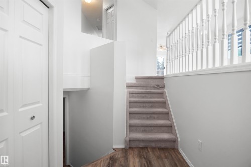 Multi-level interior featuring wood-finish flooring, carpeted stairs, white painted balusters, and white paneled doors - 907 Jordan Crescent Nw, Edmonton, AB - Indoor Photo Showing Other Room