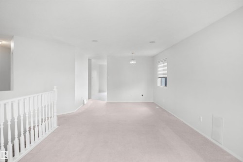 White painted walls, light-colored carpet, white railing, window with horizontal blinds, and a suspended light fixture - 907 Jordan Crescent Nw, Edmonton, AB - Indoor Photo Showing Other Room