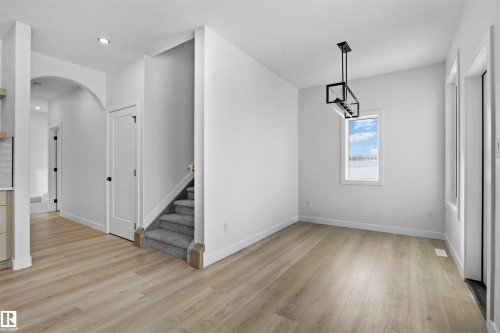 Recessed lighting, wood-finish flooring, arched doorway, contemporary stairwell with carpeted treads, and a modern rectangular chandelier - 3304 Chickadee Drive Nw, Edmonton, AB - Indoor Photo Showing Other Room