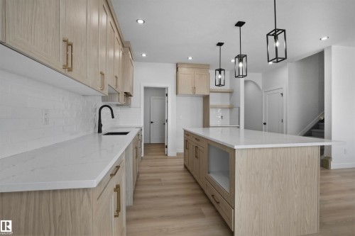 Spacious kitchen featuring an expansive island, light wood-finish cabinetry, white countertops, recessed lighting, and modern pendant light fixtures - 3304 Chickadee Drive Nw, Edmonton, AB - Indoor Photo Showing Kitchen With Upgraded Kitchen