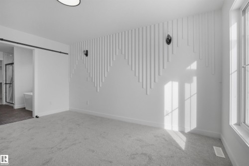 Patterned accent wall with integrated sconce lighting, large window, ceiling-mounted light fixture, and light-toned carpeting - 3304 Chickadee Drive Nw, Edmonton, AB - Indoor Photo Showing Other Room