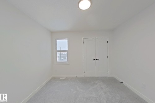 Neutral wall color, light gray carpet, recessed window, and white double panel doors - 3158 Magpie Way Nw, Edmonton, AB - Indoor Photo Showing Other Room