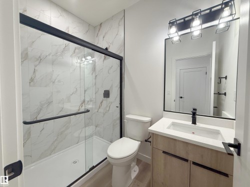 Glass-enclosed shower with a black frame and tile surround - 3158 Magpie Way Nw, Edmonton, AB - Indoor Photo Showing Bathroom