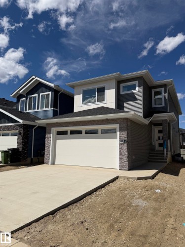 Contemporary exterior featuring horizontal siding, stone veneer accents, and a concrete driveway - 3158 Magpie Way Nw, Edmonton, AB - Outdoor With Facade