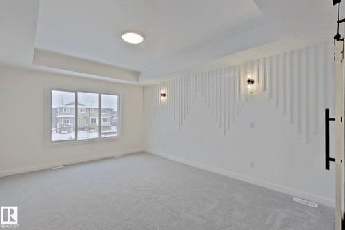 Tray ceiling with recessed lighting, wall-mounted sconces, decorative wall paneling, and a large window - 3158 Magpie Way Nw, Edmonton, AB - Indoor Photo Showing Other Room