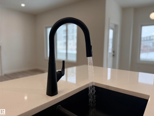 Matte black gooseneck faucet with an integrated black sink, set within a light-toned countertop - 3158 Magpie Way Nw, Edmonton, AB - Indoor Photo Showing Kitchen