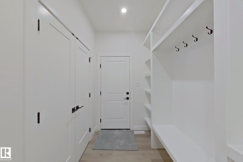Entryway featuring light wood-finish flooring, built-in shelving, a built-in bench, and black hardware on doors - 3158 Magpie Way Nw, Edmonton, AB - Indoor Photo Showing Other Room