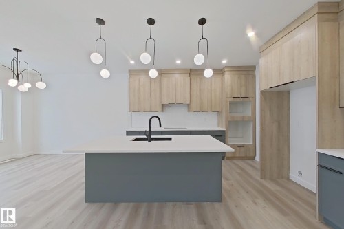 Contemporary kitchen featuring a central island with an integrated sink, light wood-finish cabinetry, and recessed lighting - 3158 Magpie Way Nw, Edmonton, AB - Indoor Photo Showing Kitchen With Upgraded Kitchen
