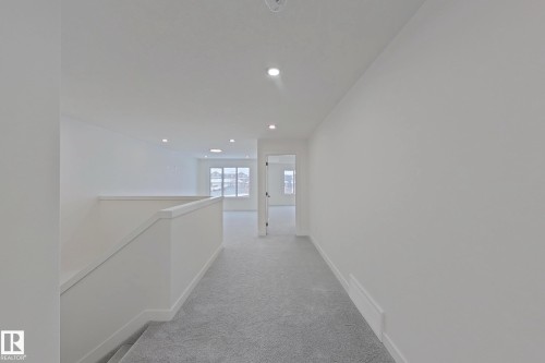 Carpeted hallway with recessed lighting and a white painted banister - 3158 Magpie Way Nw, Edmonton, AB - Indoor Photo Showing Other Room