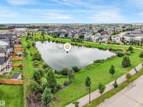 Neighborhood featuring a central pond with a fountain, surrounded by green spaces and paved pathways - 27 Kingdom Place, Leduc, AB - Outdoor With View