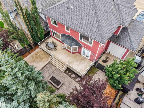 Expansive multi-level wood-finish deck with white railings, featuring a lower paver patio with a built-in fire pit - 27 Kingdom Place, Leduc, AB - Outdoor With Deck Patio Veranda