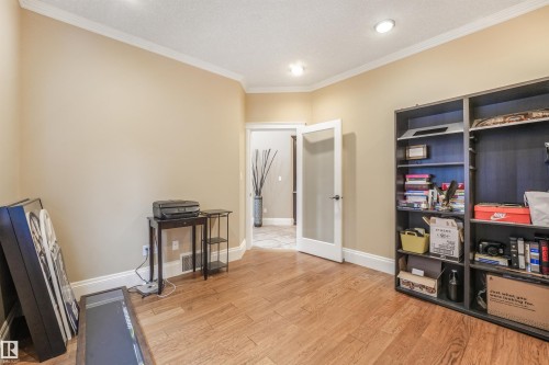 Wood-finish flooring with crown molding and recessed lighting - 27 Kingdom Place, Leduc, AB - Indoor Photo Showing Other Room