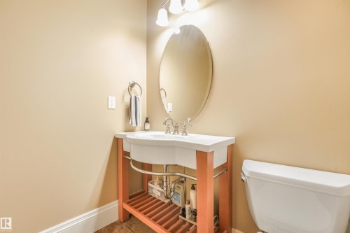 Open-shelf vanity with a basin sink, chrome faucet, oval mirror, and wall-mounted lighting - 27 Kingdom Place, Leduc, AB - Indoor Photo Showing Bathroom