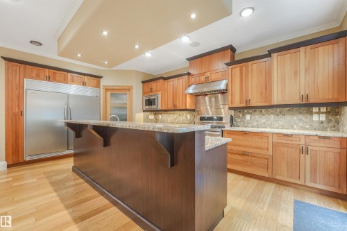 Kitchen featuring wood-finish flooring, two-tone cabinetry, stainless steel appliances, a center island with a stone countertop, and recessed lighting - 27 Kingdom Place, Leduc, AB - Indoor Photo Showing Kitchen With Upgraded Kitchen