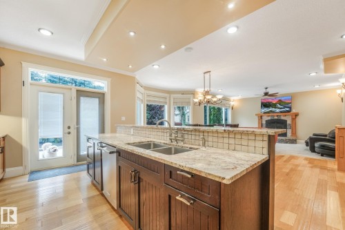 Kitchen island with granite countertop and double basin sink - 27 Kingdom Place, Leduc, AB - Indoor Photo Showing Kitchen With Double Sink