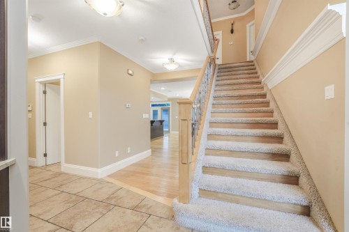 Staircase with wood newel posts, metal balusters, and carpeted treads - 27 Kingdom Place, Leduc, AB - Indoor Photo Showing Other Room