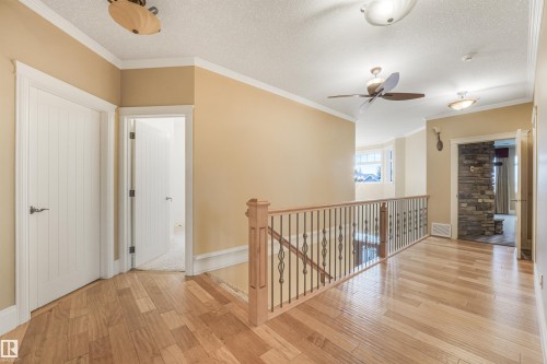 Wood-finish flooring throughout, with white panel doors and crown molding - 27 Kingdom Place, Leduc, AB - Indoor Photo Showing Other Room