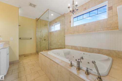 Built-in soaking tub with deck-mounted fixtures, glass-enclosed shower, transom window, and tile flooring - 27 Kingdom Place, Leduc, AB - Indoor Photo Showing Bathroom