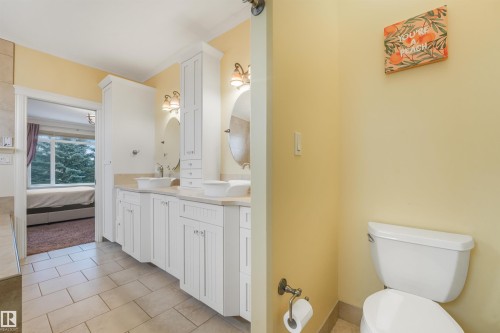 Tile flooring leading to a dual vanity with undermount sinks, wall-mounted mirrors, and sconce lighting - 27 Kingdom Place, Leduc, AB - Indoor Photo Showing Bathroom
