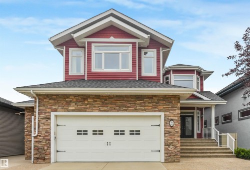 Two-story residence featuring a stone-clad facade, red siding, and white trim - 27 Kingdom Place, Leduc, AB - Outdoor With Facade