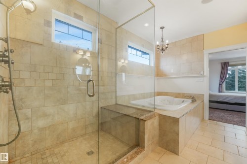 Tiled walk-in shower with glass enclosure, built-in bench, and a jetted soaking tub - 27 Kingdom Place, Leduc, AB - Indoor Photo Showing Bathroom