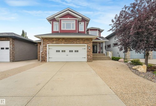 Stone veneer and siding exterior, concrete driveway, attached garage, covered entry, and mature landscaping - 27 Kingdom Place, Leduc, AB - Outdoor With Facade