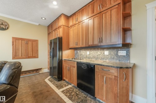 Full-height cabinetry, stone backsplash, under-cabinet lighting, integrated sink, and built-in dishwasher - 27 Kingdom Place, Leduc, AB - Indoor Photo Showing Kitchen
