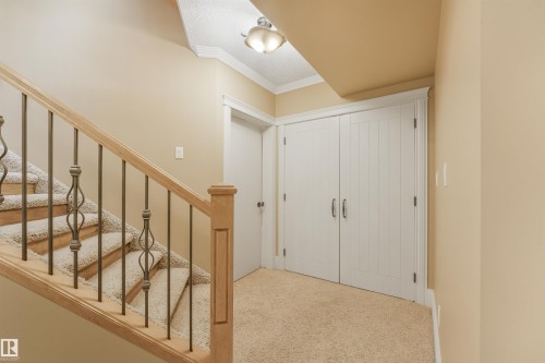 Carpeted staircase with wood handrail and wrought iron balusters, recessed lighting, and white paneled bi-fold doors - 27 Kingdom Place, Leduc, AB - Indoor Photo Showing Other Room