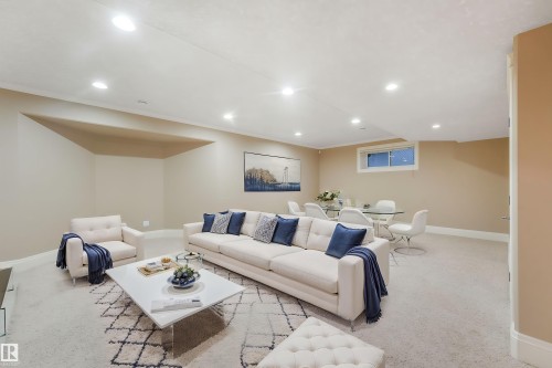 Recessed lighting illuminates this open-concept room featuring neutral-toned walls, white trim, and a window with a white frame - 27 Kingdom Place, Leduc, AB - Indoor
