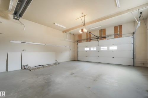 Spacious garage with polished concrete flooring, overhead sectional garage door with multiple panels, recessed and pendant lighting throughout, and white drywall walls providing a bright, clean interior - 27 Kingdom Place, Leduc, AB - Indoor Photo Showing Garage