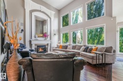 Expansive living area featuring soaring ceilings, a decorative fireplace with an ornate mantel, and a multi-pane window wall - 