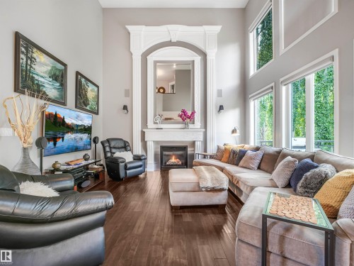 High ceilings, fireplace with ornate mantel, wood-finish flooring, and multiple large windows - 967 Lamb Crescent Nw, Edmonton, AB - Indoor Photo Showing Living Room With Fireplace