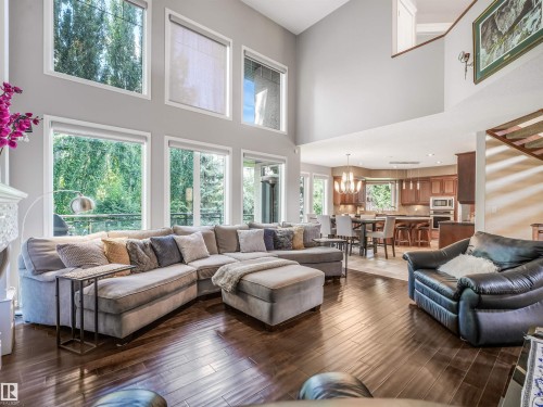 Two-story living area with high ceilings, dark wood-finish flooring, and a wall of windows - 967 Lamb Crescent Nw, Edmonton, AB - Indoor Photo Showing Living Room