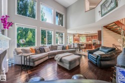 Two-story great room with abundant natural light, rich wood-finish flooring, and a fireplace with tile surround - 
