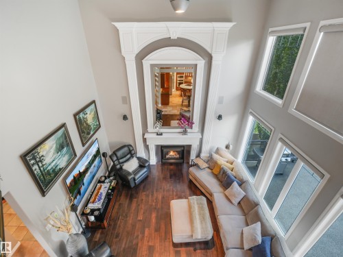 Vaulted ceiling, prominent fireplace with ornate mantel, dark wood-finish flooring, multiple large windows, and built-in wall sconces - 967 Lamb Crescent Nw, Edmonton, AB - Indoor With Fireplace
