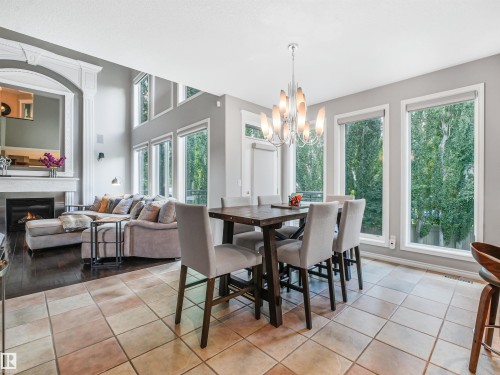 Open-concept living space with high ceilings and expansive windows - 967 Lamb Crescent Nw, Edmonton, AB - Indoor Photo Showing Dining Room With Fireplace