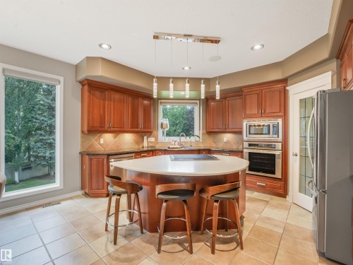 Kitchen featuring wood-finish cabinetry, stainless steel appliances, a center island with a cooktop, and tile flooring - 967 Lamb Crescent Nw, Edmonton, AB - Indoor