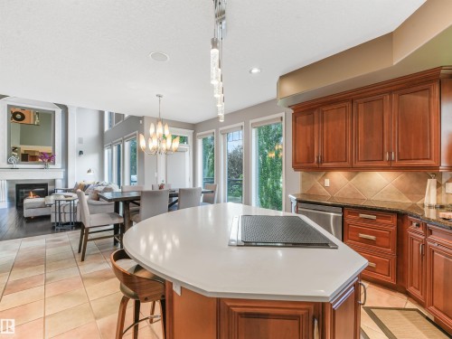 Gourmet kitchen with an integrated cooktop on the island, rich wood cabinetry, and a tile backsplash - 967 Lamb Crescent Nw, Edmonton, AB - Indoor Photo Showing Kitchen With Fireplace With Upgraded Kitchen