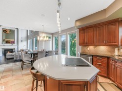 Gourmet kitchen with an integrated cooktop on the island, rich wood cabinetry, and a tile backsplash - 