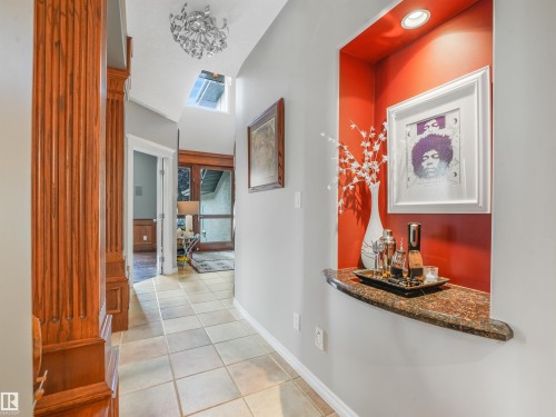 Hallway featuring tile flooring, a decorative niche with recessed lighting and a stone slab, a skylight, and a decorative ceiling fixture - 967 Lamb Crescent Nw, Edmonton, AB - Indoor Photo Showing Other Room