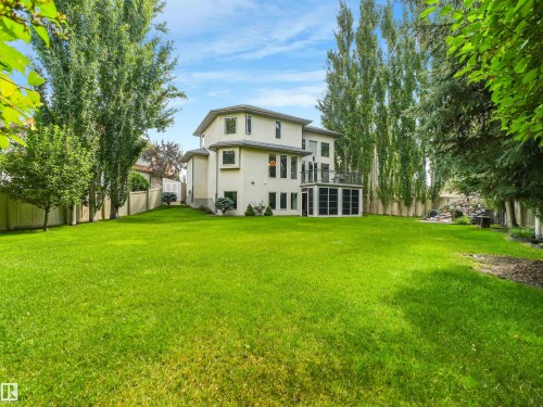 Expansive backyard featuring a manicured lawn, mature trees, and a multi-level dwelling with a balcony and screened-in enclosure - 967 Lamb Crescent Nw, Edmonton, AB - Outdoor