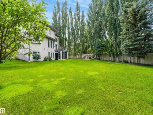 Expansive green lawn, stucco exterior, enclosed patio, upper-level balcony, and mature perimeter trees - 967 Lamb Crescent Nw, Edmonton, AB - Outdoor
