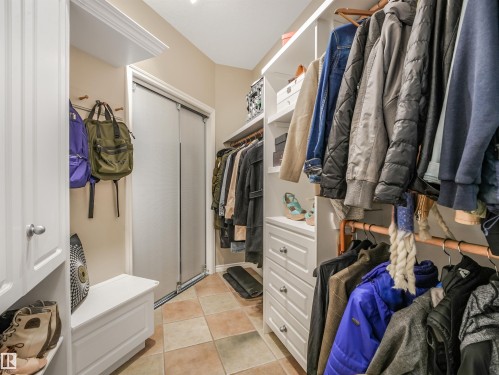 Built-in cabinetry with crown molding, integrated shelving, pull-out drawers, and durable tile flooring - 967 Lamb Crescent Nw, Edmonton, AB - Indoor With Storage