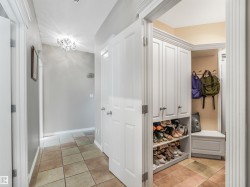 Hallway featuring tile flooring, a decorative ceiling light fixture, white interior doors, and a built-in storage unit with open shelving and an integrated bench - 