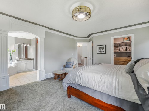 Recessed ceiling fan, arched doorway with decorative columns, tiled bathroom flooring, double vanity, and built-in closet shelving - 967 Lamb Crescent Nw, Edmonton, AB - Indoor Photo Showing Bedroom